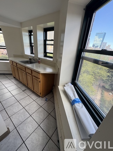 A kitchen with a wooden cabinet and a window overlooking a cityscape.
