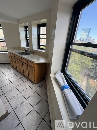 A kitchen with a wooden cabinet and a window overlooking a cityscape.