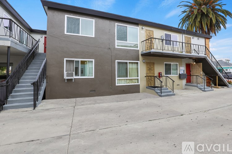 A building with a balcony and a palm tree in the background.