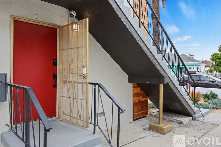 A red door is on the left side of a staircase.