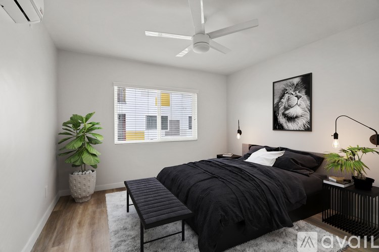 A bedroom with a bed, a bench, and a plant.