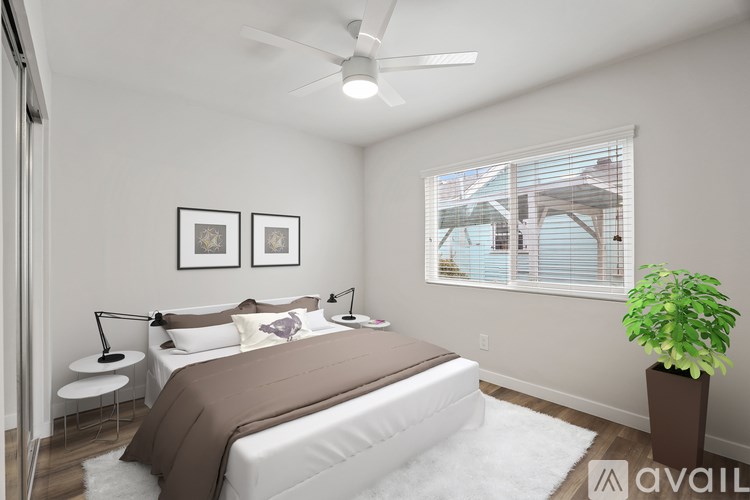 A bedroom with a bed, two lamps, a plant, and pictures on the wall.