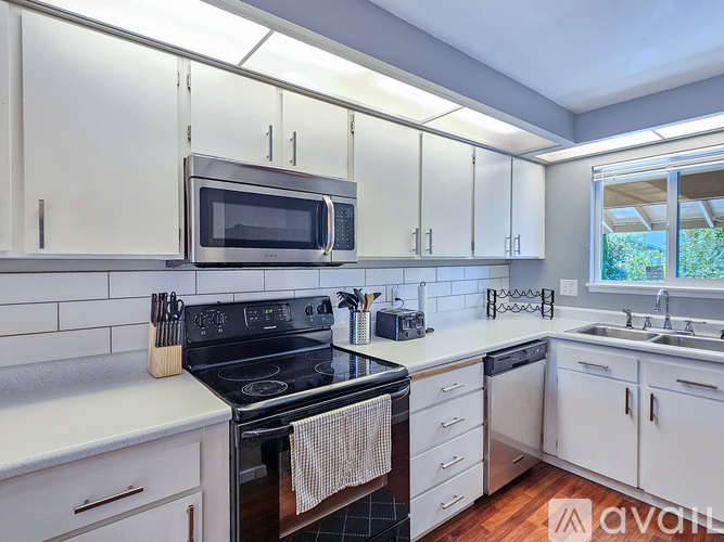 A kitchen with white cabinets and a black stove top.