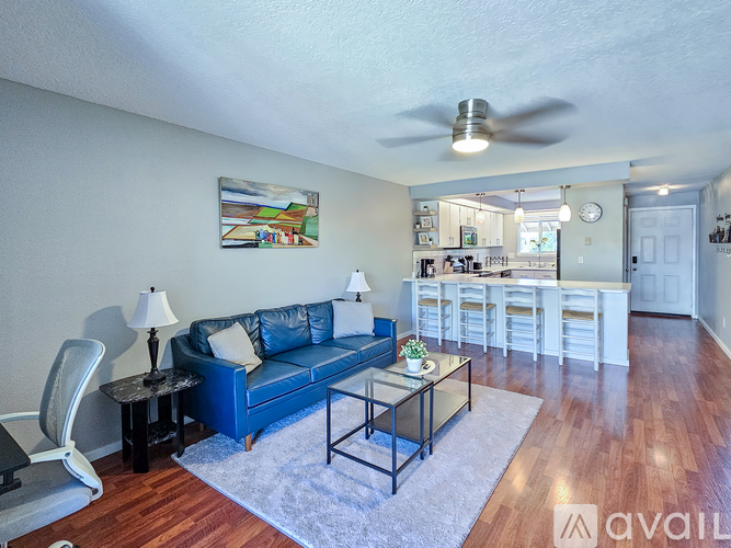 A living room with a blue couch, a chair, a table with a lamp, and a painting on the wall.