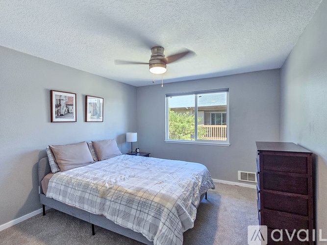 A bedroom with a bed, dresser, and window.