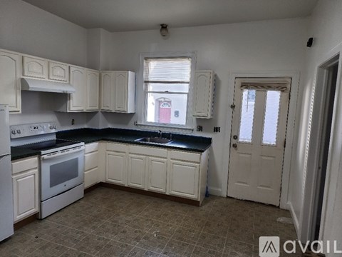 A kitchen with white cabinets and a black countertop.