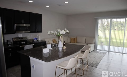 A kitchen with black cabinets and a white island.
