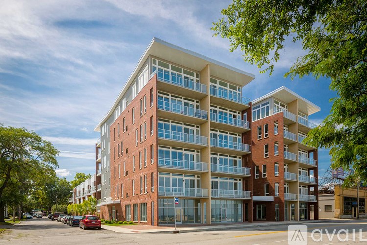 A modern apartment building with red brick and large windows is available for rent.