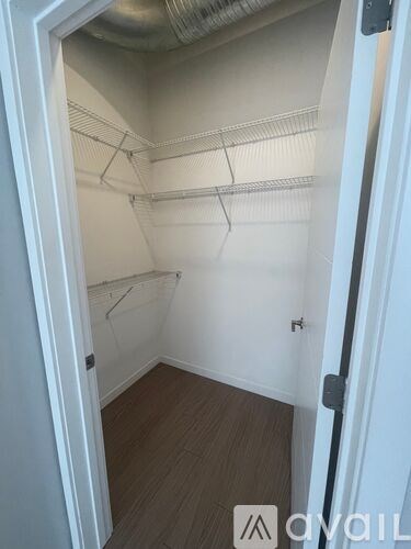 A white door is open to a small, empty room with a wooden floor and white walls.