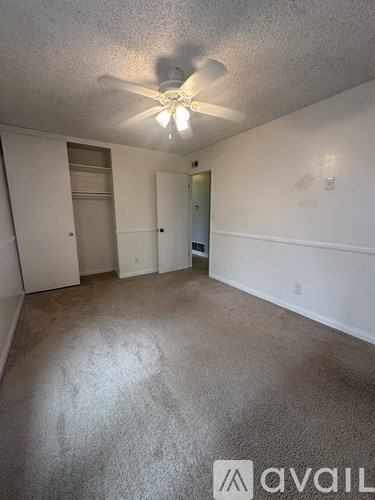 A room with a ceiling fan and carpeted floor.