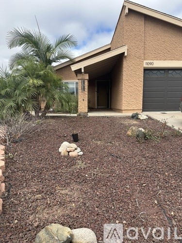 A house with a driveway and a palm tree in front.