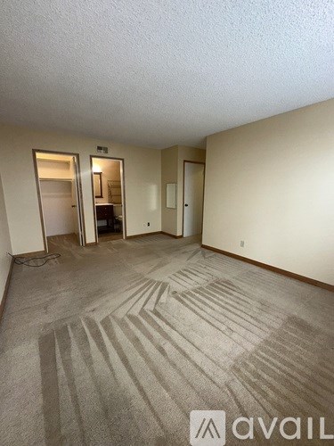 A carpeted room with a doorway leading to another room.