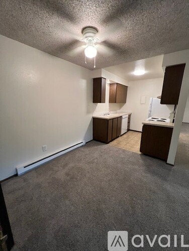 A room with a carpeted floor and a kitchenette.