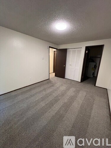 A room with carpeted floor and a door on the left.