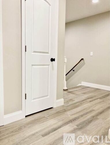 A white door is open to a hallway with a staircase.
