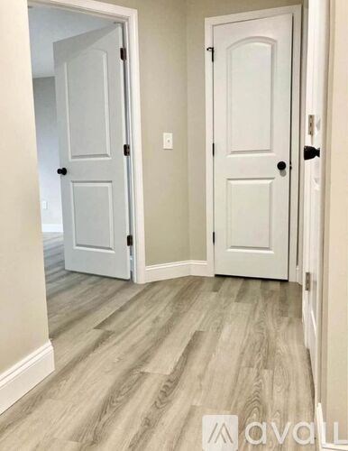 A hallway with two doors and a wooden floor.