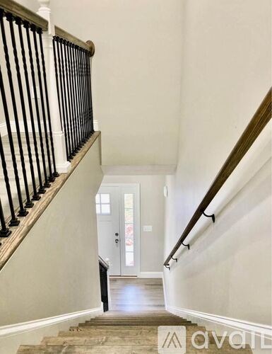 A staircase with a black railing and wooden steps leading to a white door.