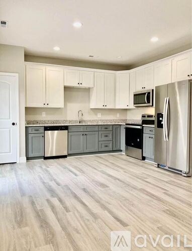 A kitchen with white cabinets and a wooden floor.