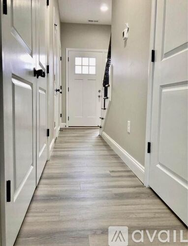 A hallway with white doors and a wooden floor.
