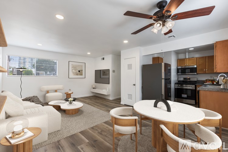 A modern living room with a white sofa, wooden chairs, and a round table.