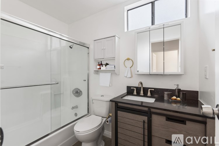 A modern bathroom with a walk-in shower, double sinks, and a toilet.