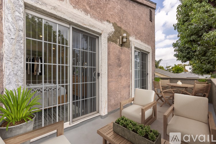 A patio with a table, chairs, and plants.