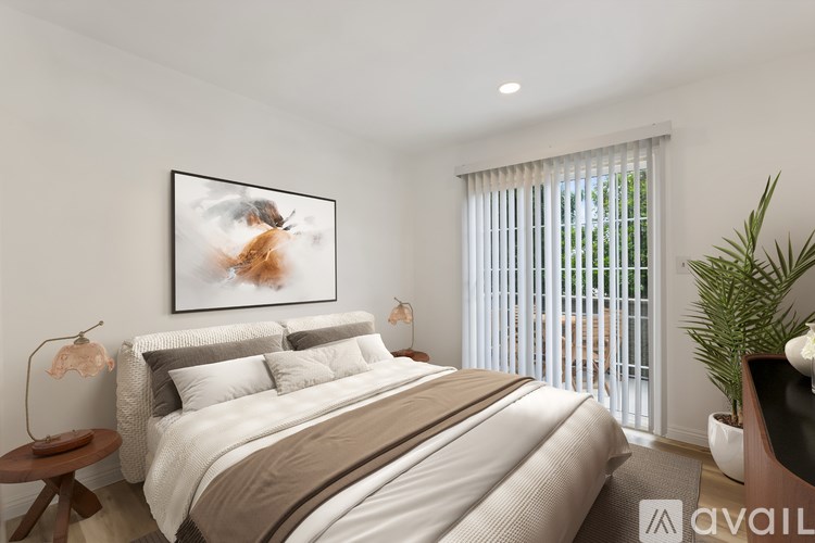 A bedroom with a large bed, a painting on the wall, and a plant on the side table.