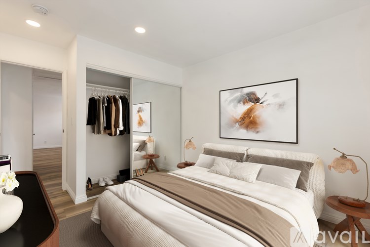 A bedroom with a large bed and a clothing rack with clothes hanging on it.