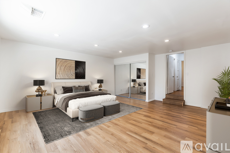 A bedroom with a large bed and a painting on the wall.