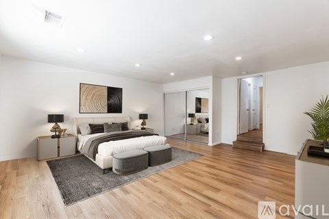 A bedroom with a large bed and a painting on the wall.