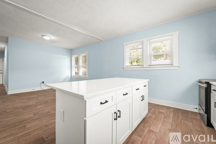 A kitchen with white cabinets and a countertop is available for rent.