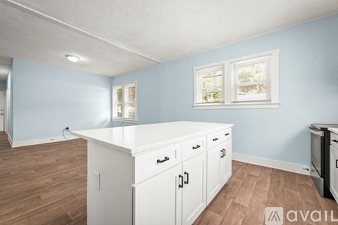 A kitchen with white cabinets and a countertop is available for rent.