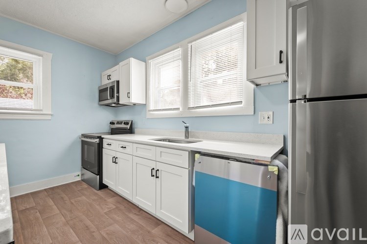 A kitchen with a blue wall and white cabinets.