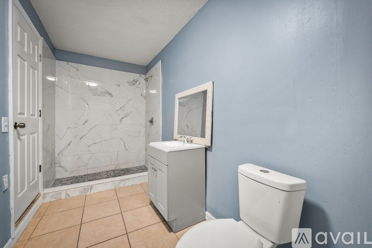 A bathroom with blue walls and a marble shower.