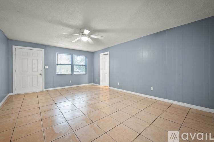 A room with a ceiling fan and tile flooring.