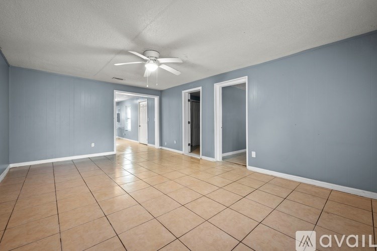 A spacious room with tile flooring and a ceiling fan.