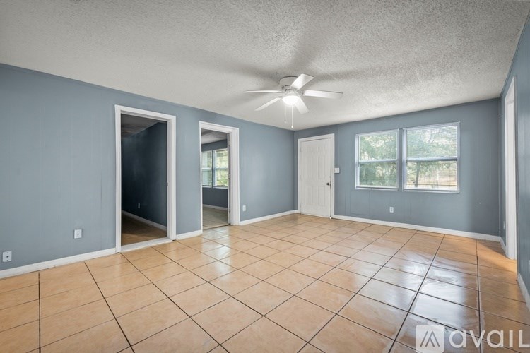 A spacious room with tile flooring and a ceiling fan.