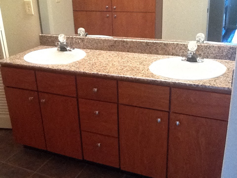 A bathroom with two sinks and brown cabinets.