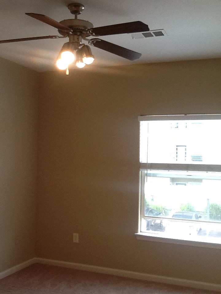 A room with a ceiling fan and a window.