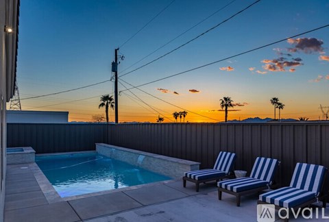 Two striped lounge chairs sit on a patio next to a pool.