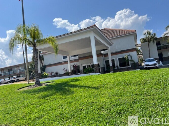 A white building with a red roof and a palm tree in front.