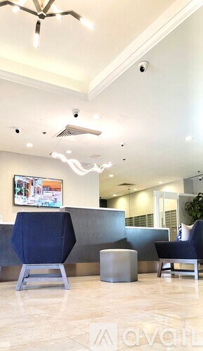 A living room with a blue chair and a grey ottoman.