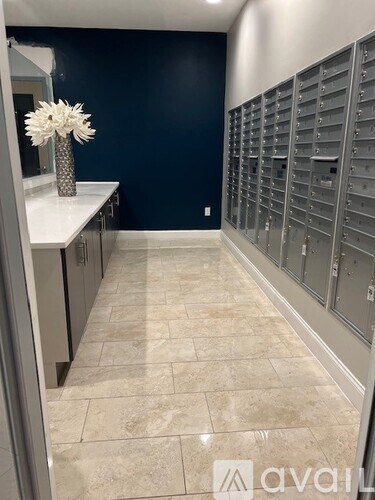 A room with a row of mailboxes on the wall and a vase with white flowers on the counter.