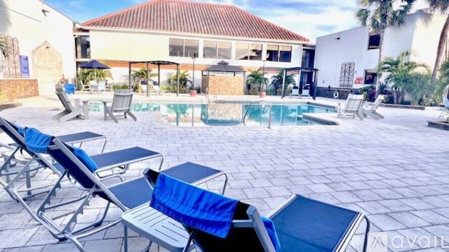 A poolside area with sun loungers and a building in the background.