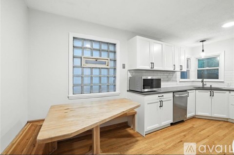 A kitchen with white cabinets and a wooden table.