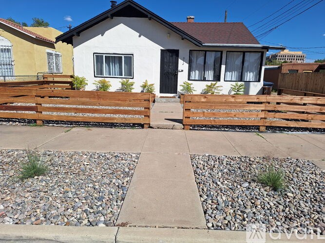 A white house with a black door and a wooden fence.