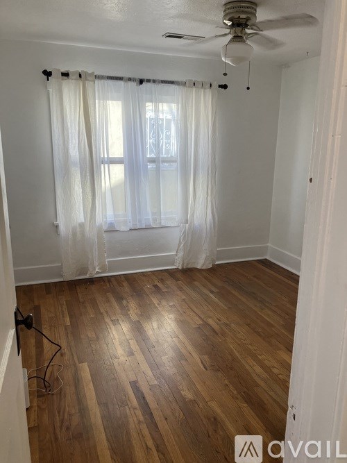 A room with wooden flooring and a ceiling fan.