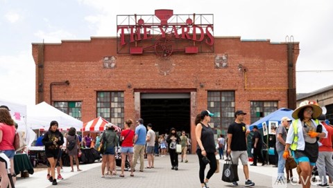 A group of people are walking in front of a red brick building with a sign that says "The Card".