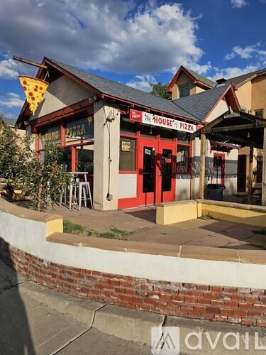 A brick building with a red door and a sign that says House's Pizza.