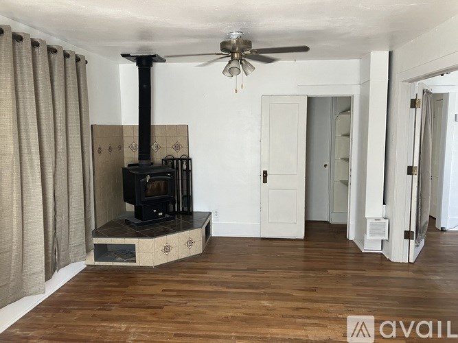 A wood stove is in a living room with a fan.